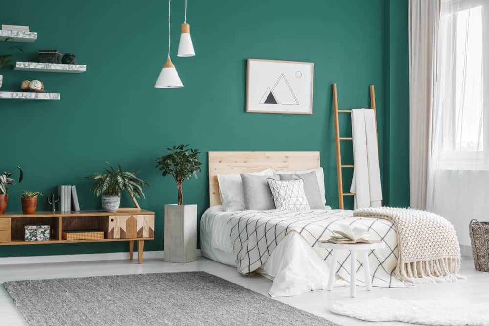 A minimalist Scandinavian style bedroom with a teal green back wall