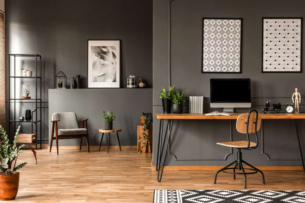 Modern office space featuring grey walls, wooden flooring and a wooden desk with hairpin table legs