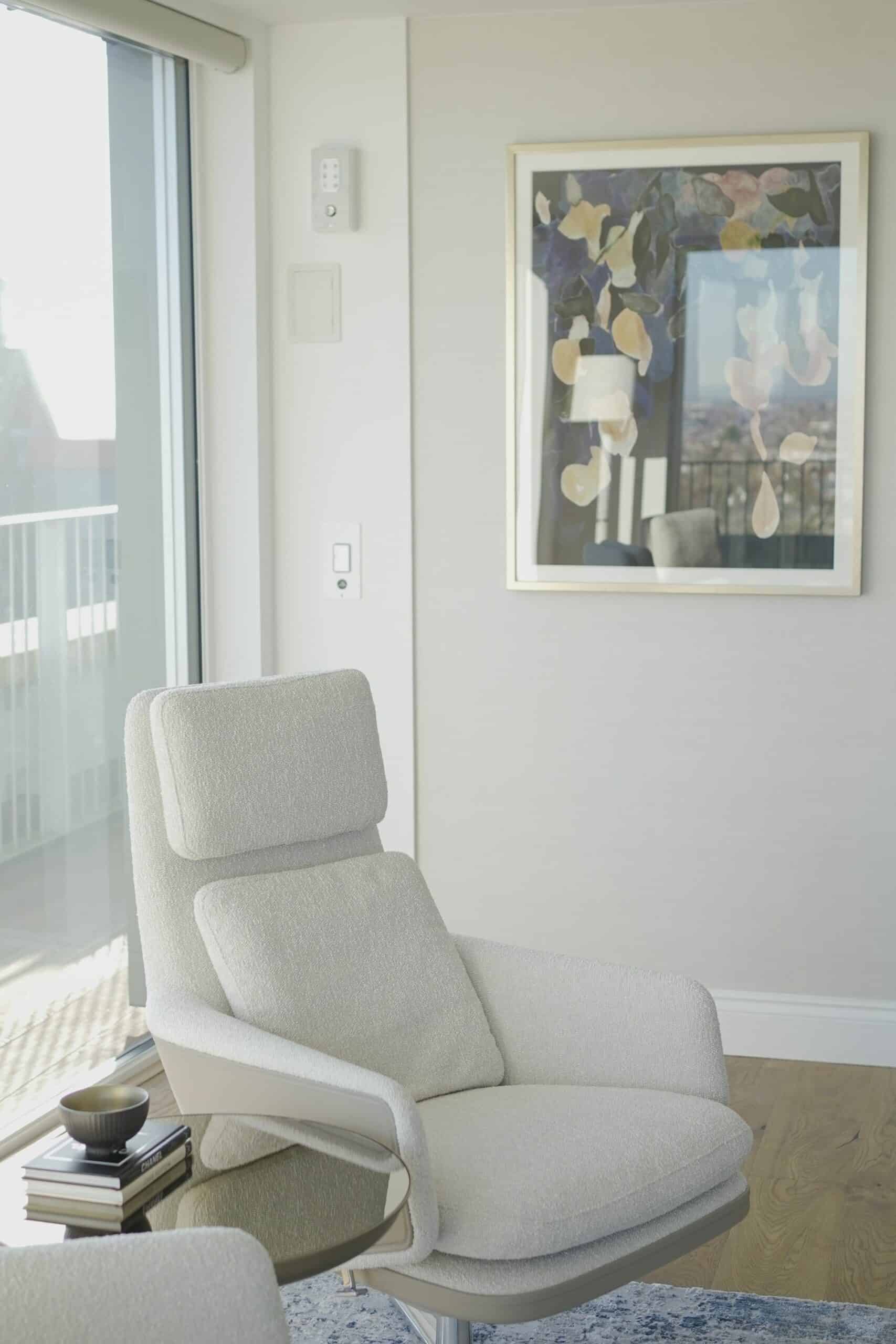 Luxury cream-coloured chair and side table in top floor apartment with modern art painting on the wall